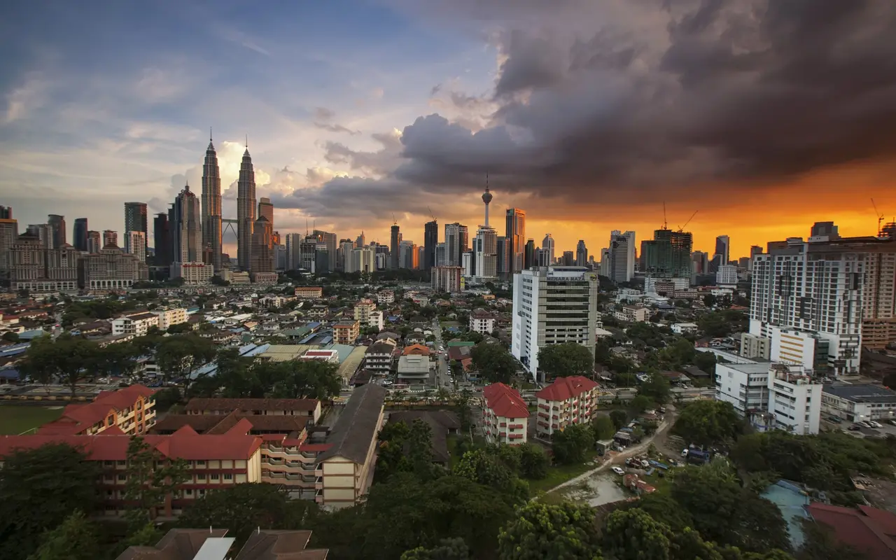 The Kuala Lumpur skyline and Petronas Towers at dusk under a stormy sky