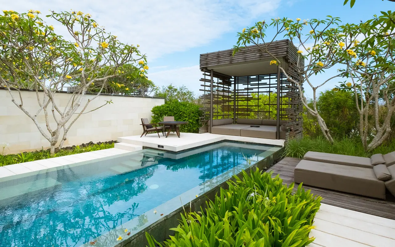 A villa pool with a timber sala, frangipani trees and a lawn